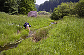 Mountainbiker erfrischt sich im Bach im Neuhöfer Tal, Pfälzerwald, Rheinland-Pfalz, Deutschland