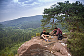 Zwei Männer beim Picknick auf Sandsteinfelsen, Pfälzerwald, Rheinland-Pfalz, Deutschland