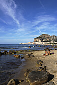 Couple on Beach, View to Cefalu with Rocca di Cefalu, Cefaly, Sicily, Italy