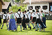 Couples wearing traditional costumes passing meadow, May Running, Antdorf, Upper Bavaria, Germany