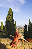 woman sitting on the western city wall, Pienza, Tuscany, Italy