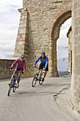 Young couple riding bicycles on a street at San Leo, Marche, Italy, Europe