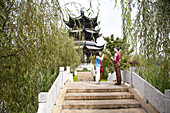 Junge Chinesin und deutsche Touristin im Gespräch auf einer Brücke im Lianhuachi Park, Kunming, Yunnan, Volksrepublik China, Asien