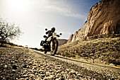 Man on motorcycle on rough-textured tarred road, Mali, Africa