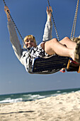 Woman on a swing on Mezizim Beach in Tel Aviv, Israel, Middle East