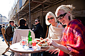 Young women sitting in a outdoor cafe at the Amagertorv shopping mile, Copenhagen, Denmark