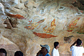 Touristen betrachten die Wandmalereien der Wolkenmädchen von Sigiriya, Sigiriya, Sri Lanka, Asien
