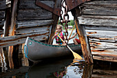A girl in a canoe between ship wrecks on the island of Norrbyskaer, Vaesterbotten, Sweden, Europe