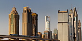 Neue Metro vor Skyline des Finanzzentrums von Dubai an der Zeihet Road