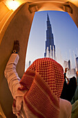 Arab Man watching Dubai Fountain at Burj Khalifa, highest Skycraper in the World, 828 meter, Burj Dubai, Dubai UEA