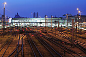Schienen und Bahnhofsgebäude, beleuchtet, Frauenkirche und Justizpalast im Hintergrund, Hauptbahnhof München, München, Oberbayern, Bayern, Deutschland