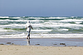 Woman walks on beach, stormy weather, Jutland, Denmark