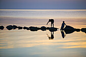 Silhouettes of children playing on a stonewall in the sea