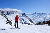 Female backcountry skier ascending to Rauchkofel, Dreiherrenspitze in background, Ahrntal, Zillertal Alpes, South Tyrol, Trentino-Alto Adige/Südtirol, Italy