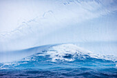 Wave crashes onto blue Antarctic iceberg, South Shetland Islands, Antarctica