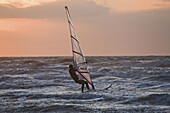 Windsurfer surfing the waves in the evening light, St Peter-Ording, Schleswig-Holstein, North Sea coast, Germany