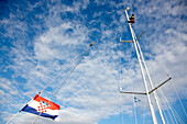 Segler am Mast einer Segelyacht unter Wolkenhimmel, Kornaten, Kroatien, Europa