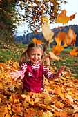 girl playing in pile of leaves, fall Zuerich, Switzerland