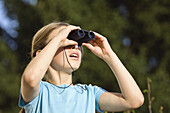 Girl looking through binoculars, Germany