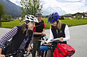 Cyclists reading map, Isar Cycle Route near Wallgau, Karwendel range, Upper Bavaria, Germany