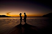 Silhouette of young couple holding hands on the beach and facing each other during sunset at Playas del Coco, Costa Rica