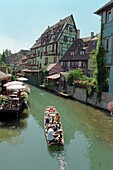 Tourists on boat passing along the waterway  Colmar, Alsace France