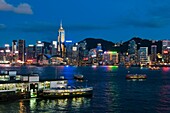 Victoria Harbour Hong Kong at dusk with Star Ferry Terminal in the foregroound  Hong Kong China