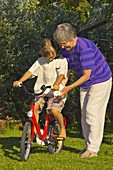 Grandmother teaching her granddaughter to ride a bicycle