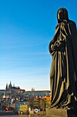 Statue on Charles Bridge with Hrad the Prague castle in the background