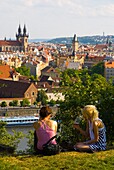Two women relaxing in Letna Park with Old Town in background in Prague Czech Republic Europe