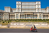 Scooter passing Palace of Parliament building in Bucharest Romania Europe