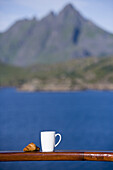 Croissant und Kaffeetasse zum Frühaufsteher-Frühstück an Bord von Kreuzfahrtschiff MS Astor (Transocean Kreuzfahrten), nahe Leknes, Lofoten, Norwegen, Europa