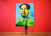 Visitor looking at portrait of Chairman Mao by Any Warhol at Hamburger Bahnhof modern art gallery in Berlin