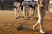 Japanese school baseball team raking sand on field after practice game