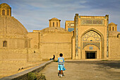 Girl walking towards Mir-i Arab madrassa, Bukhara, Uzbekistan