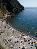 Sunbathers on the beach at Riomaggiore in the Cinque Terre region of the Italian Riviera or Riviera di Levanto