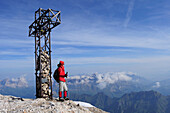 Frau steht am Gipfelkreuz der Marmolata, Dolomiten, Trentino-Südtirol, Italien