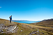 Wanderer blickt auf den See Torneträsk, Lappland, Nordschweden, Schweden