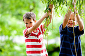 Two boys (6 - 7 years) holding on twigs