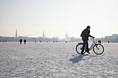 Cyclist on frozen outer Alster in winter, Hamburg, Germany