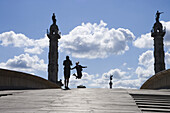 Mädchen springen auf Holzbrücke mit Statuen im Hintergrund, Bordeaux, Gironde, Aquitanien, Frankreich, Europa