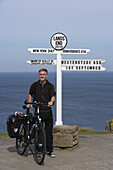 Cyclist at John O'Groats signpost, Land's End, Cornwall, England, Europe