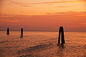 Sunset on the laguna, Bricole or Wooden posts to limit navigation zones, Venice, Italy
