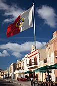 Malta, Southeast, Marsaxlokk, waterfront buildings and flag