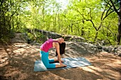 Young brunette woman doing yoga poses in a forest setting in the springtime.