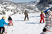 Family skiing, Schlosslelift, Hirschegg in background, Kleinwalsertal, Vorarlberg, Austria