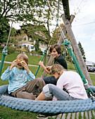 Children sitting in a basket swing at the organic Hotel Chesa Valisa, Hirschegg, Kleinwalsertal, Austria