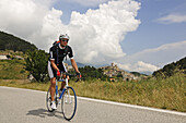 Cyclist in front of Castel del Monte, Monte Prena, Monte Camicia, Gran Sasso National Park, Abruzzi, Italy, Europe