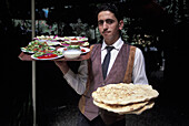 Mezze dishes and freshly baked pastries being carried in a restaurant, Amman, Jordan