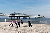 Women stretchig at beach, pier in background, Heringsdorf, Usedom, Mecklenburg-Vorpommern, Germany